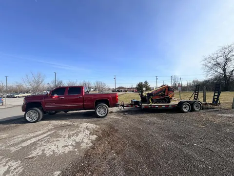 A pickup and trailer loaded with the stump grinder, ready for the next job.