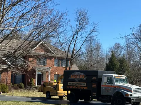 An Adkins bucket truck and chip truck parked in a driveway on a full removal.